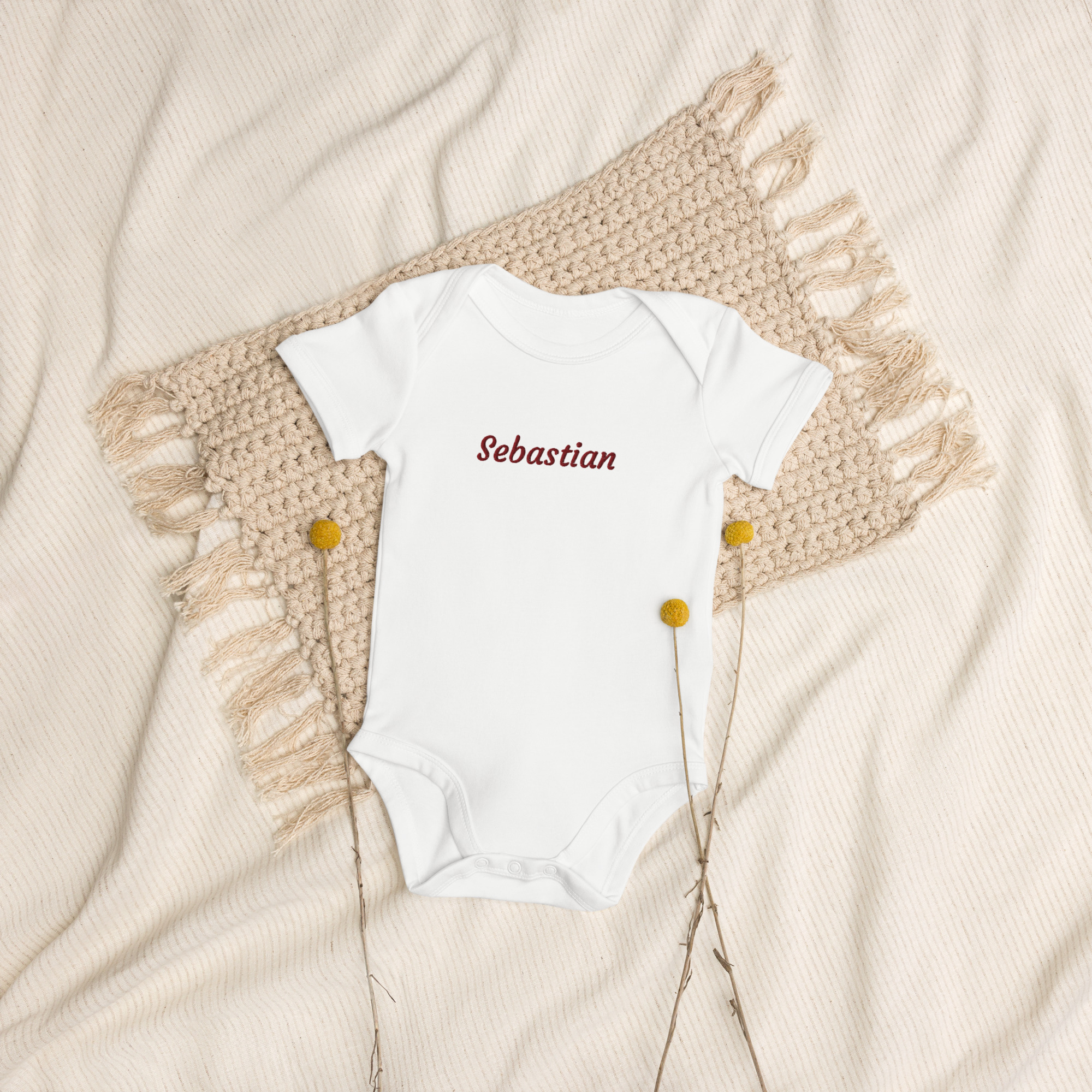Personalised baby bodysuit on soft blanket with dried flowers